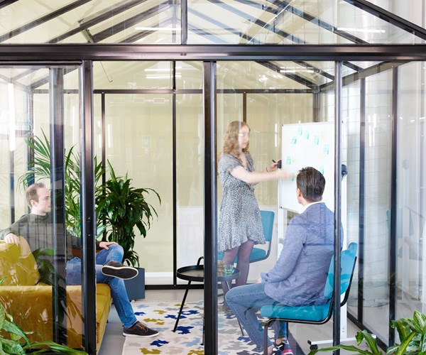 een groep mensen die in een kamer met glazen wanden zit