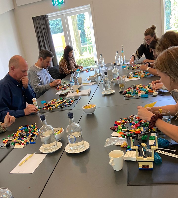 een groep mensen die rond een tafel zitten en een bordspel spelen