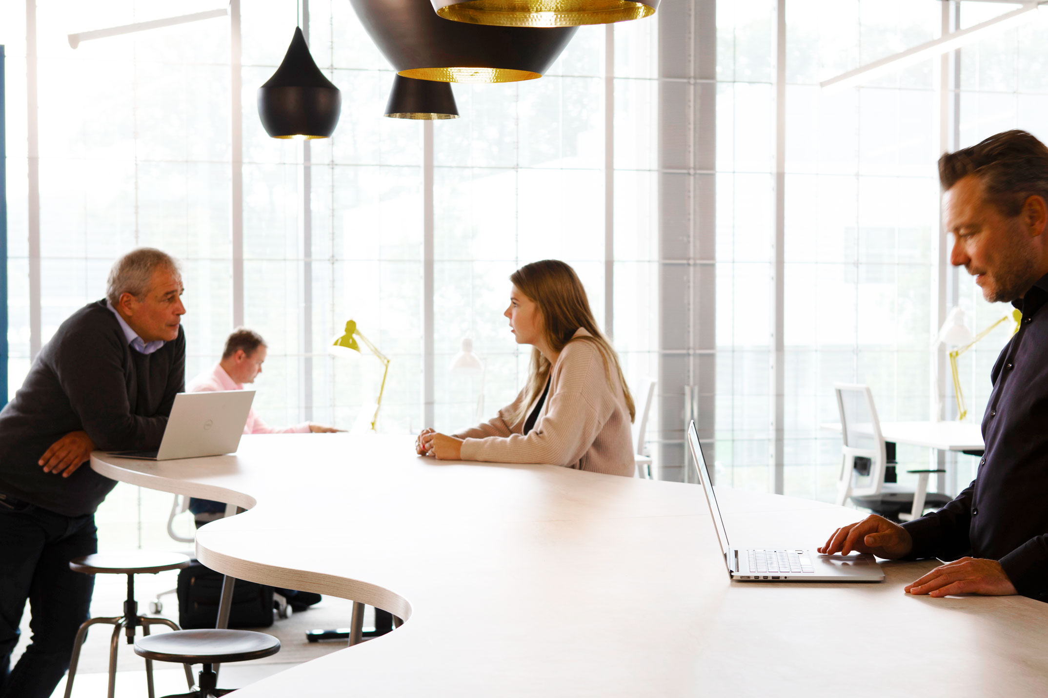 een groep mensen die rond een tafel met laptops zitten